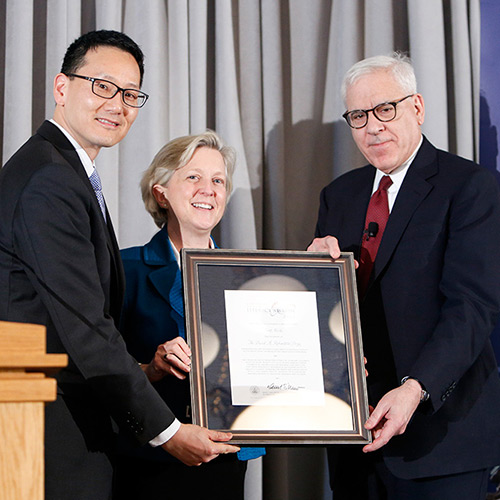 Kyle Zimmer, representing First Book, receives the 2015 Library of Congress Literacy Awards David M. Rubenstein Prize, presented by David M. Rubenstein (right) and Acting Librarian of Congress David Mao (left).